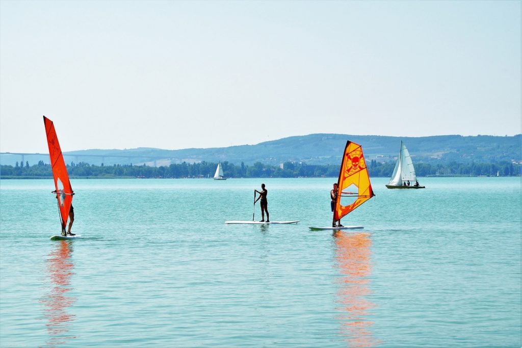 persone che fanno windsurf sul lago