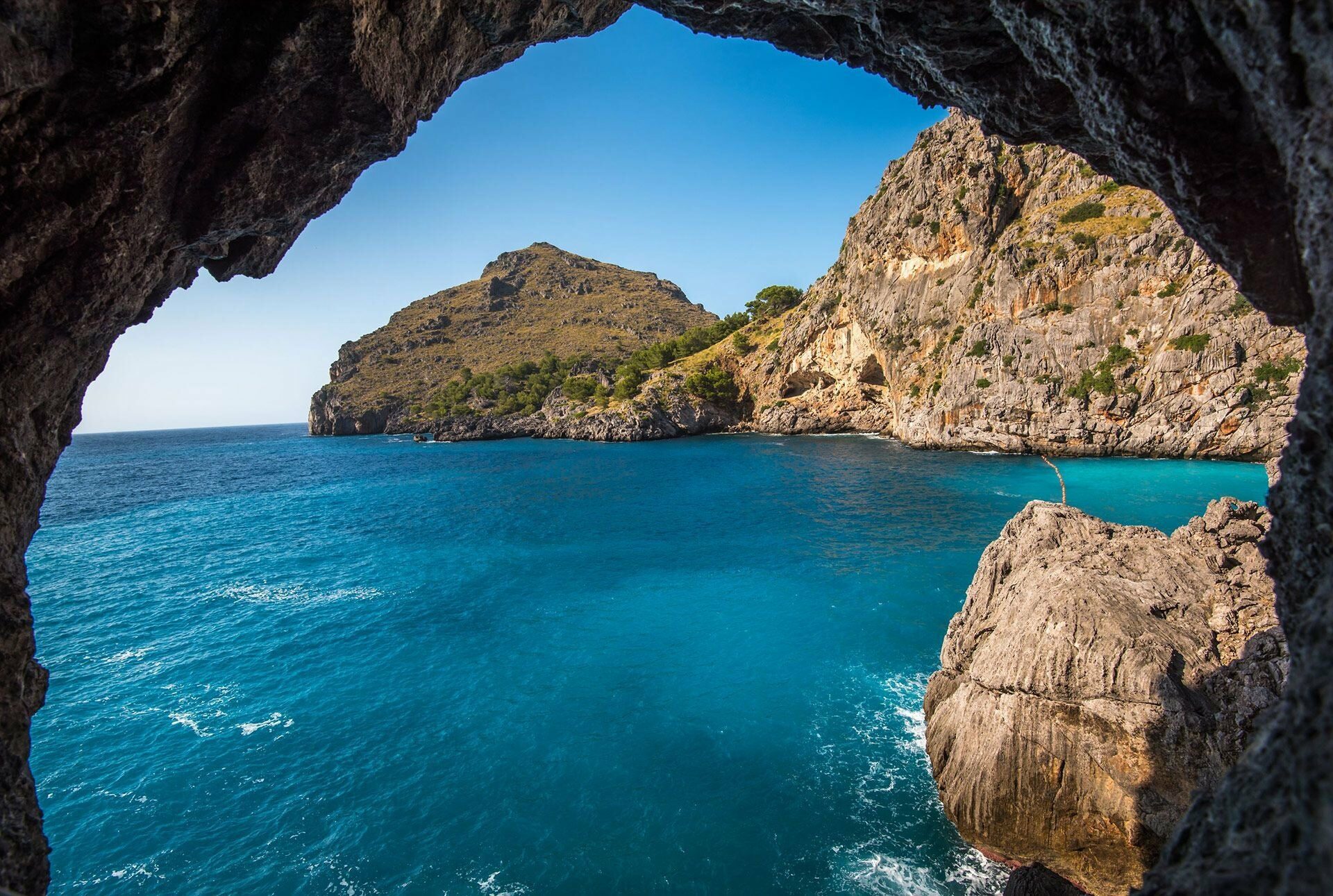 Fotografia scattata dentro una grotta con vista sul mare blu intenso e sulla costa pugliese