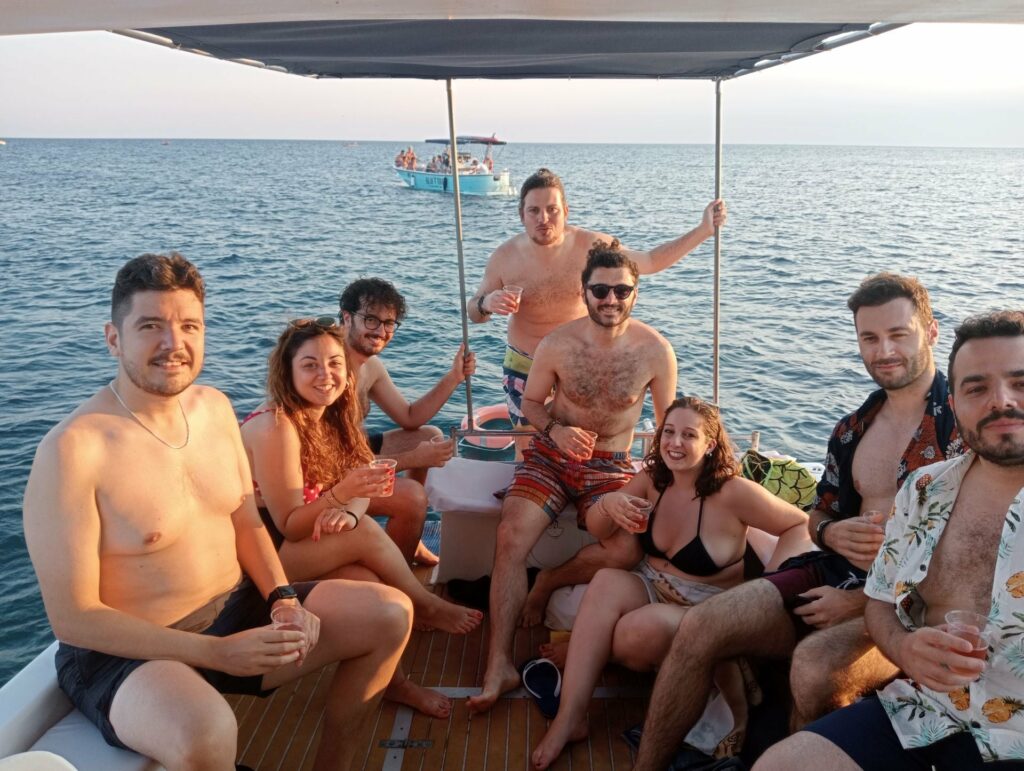 Gruppo di donne e uomini a bordo di una barca che fanno aperitivo con il mare del Salento sullo sfondo