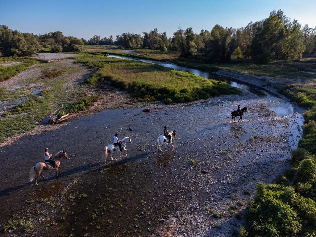Persone a cavallo che attraversano un fiume in Lombardia