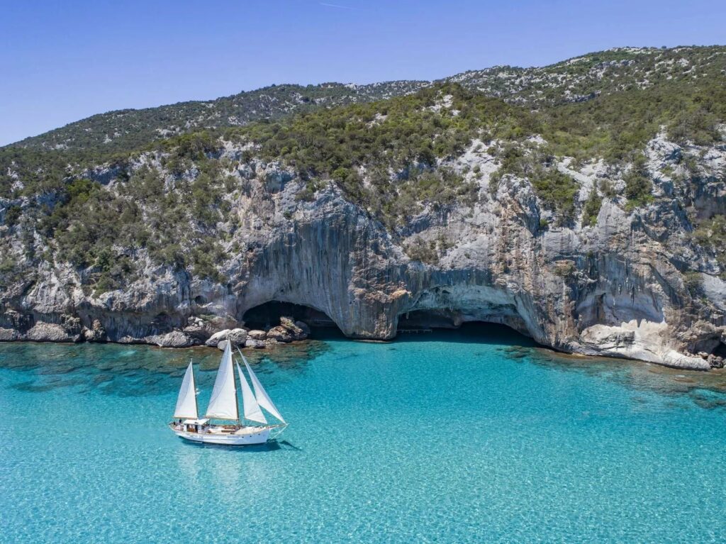 Barca a vela bianca che naviga nel mare turchese della Sardegna