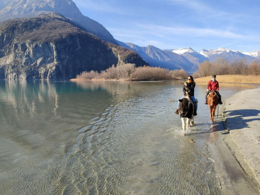 persone che fanno una passeggiata a cavallo nel fiume in Valtellina