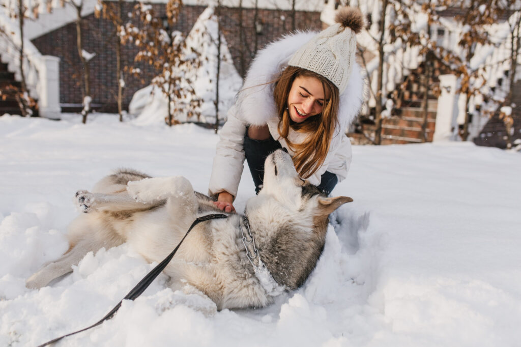 ragazza che abbraccia un cane bianco sulla neve