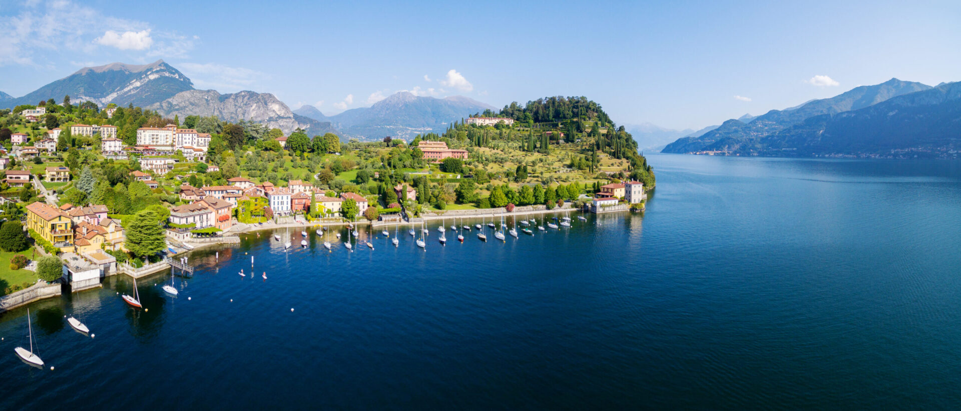 Panorama mozzafiato del Lago di Como con ville storiche, borghi pittoreschi e barche ormeggiate, ideale per vivere esperienze autentiche tra natura, cultura e relax sul lago di Como.