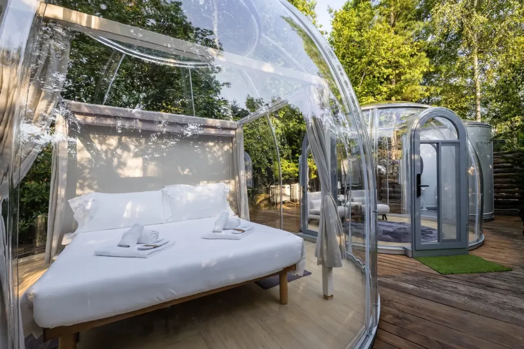 Bubble room in Piemonte con cupola trasparente e letto matrimoniale su pedana in legno, immersa nel verde