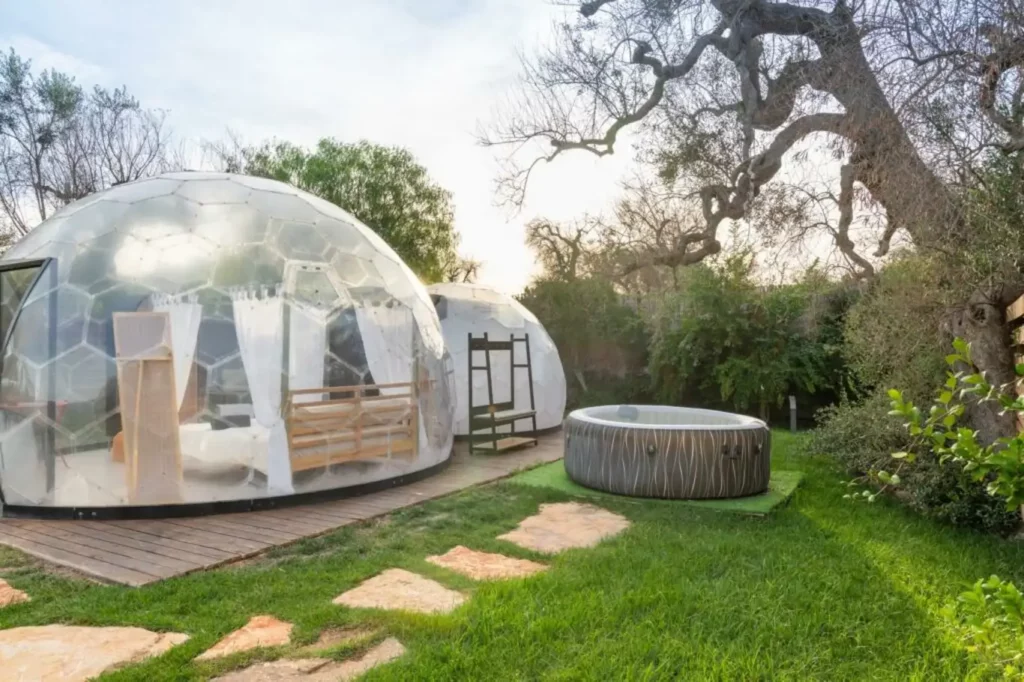 Bubble room in Puglia con cupola trasparente e vasca idromassaggio esterna, immersa nel giardino