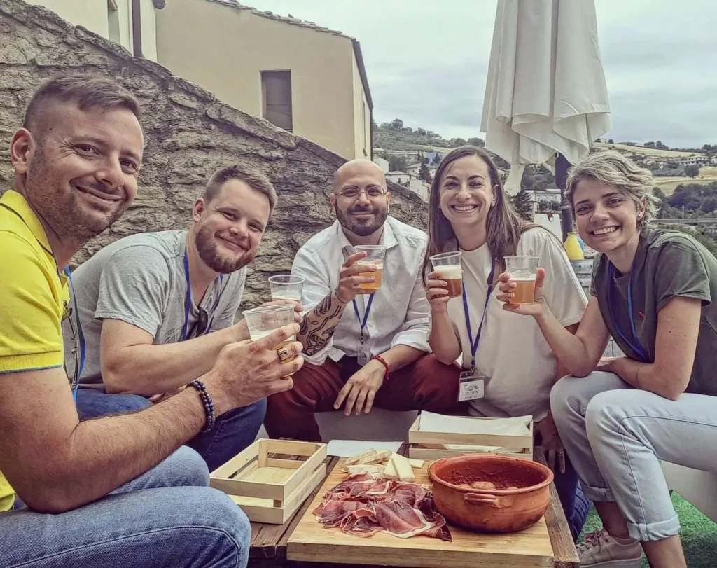 Gruppo di amici brinda con bicchieri di birra durante una degustazione birra in Abruzzo, in contesto storico