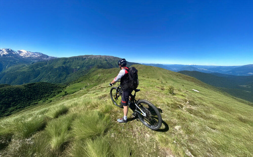 MTB a Montecampione, biker su cresta panoramica tra prati d’alta quota e vista sulla valle