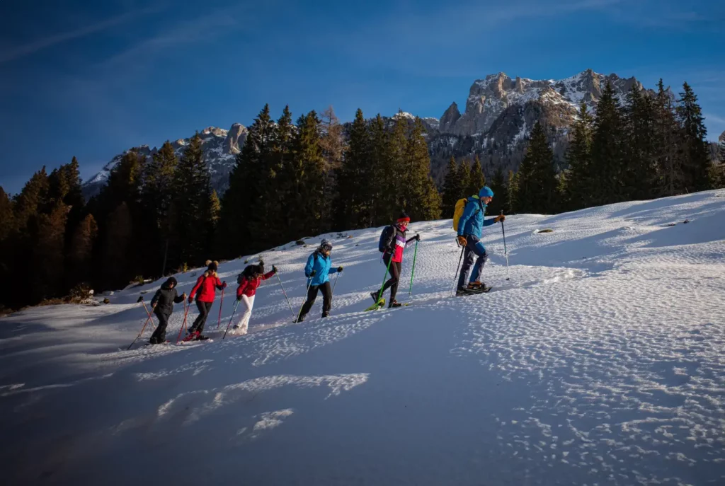 Escursione con ciaspole a Madonna di Campiglio sulle Dolomiti, salita su pendio innevato con panorama alpino