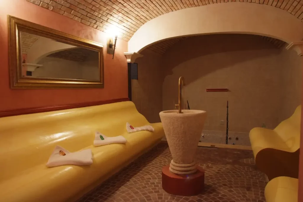 Area relax con divani gialli, asciugamani piegati e vasca idromassaggio in ambiente con volte: giornata in spa a Milano