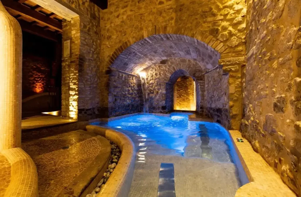 Piscina termale in grotta con archi in pietra e luci calde, perfetta per una giornata in spa a Rimini.