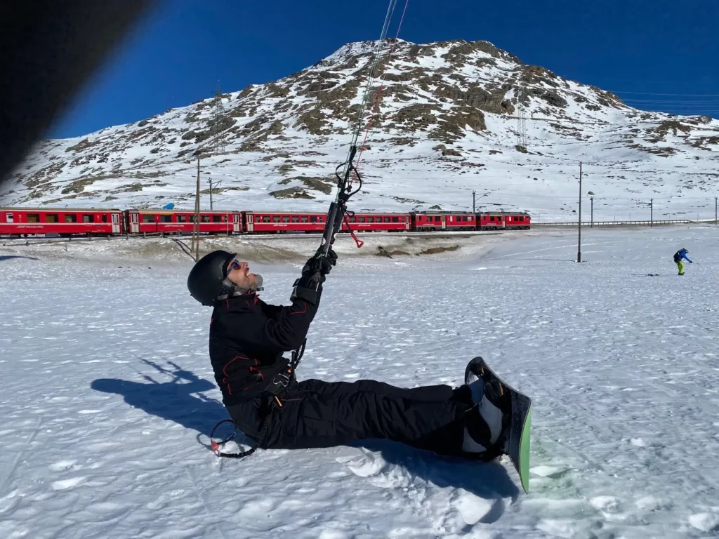 Snowkite a Madesimo in inverno, rider con snowboard e aquilone sulla neve con montagne sullo sfondo