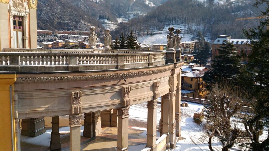 Edificio storico con colonnato e statue in Val Brembana, con paese innevato e montagne sullo sfondo
