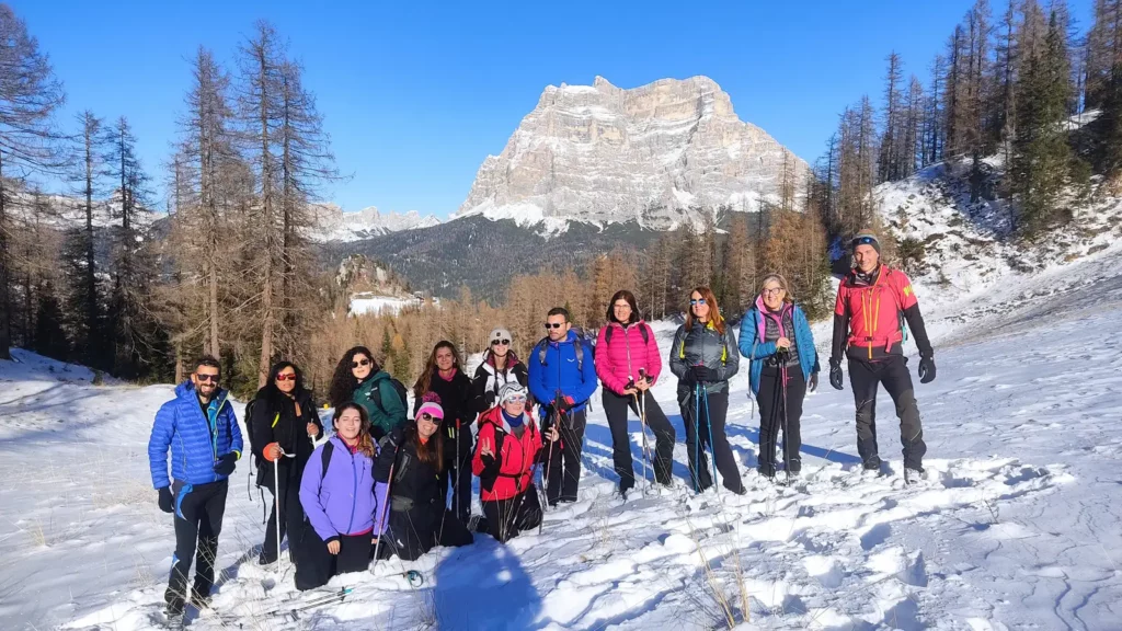 Ciaspolata in Val di Zoldo ai piedi del Monte Civetta, gruppo in escursione sulla neve con panorama dolomitico