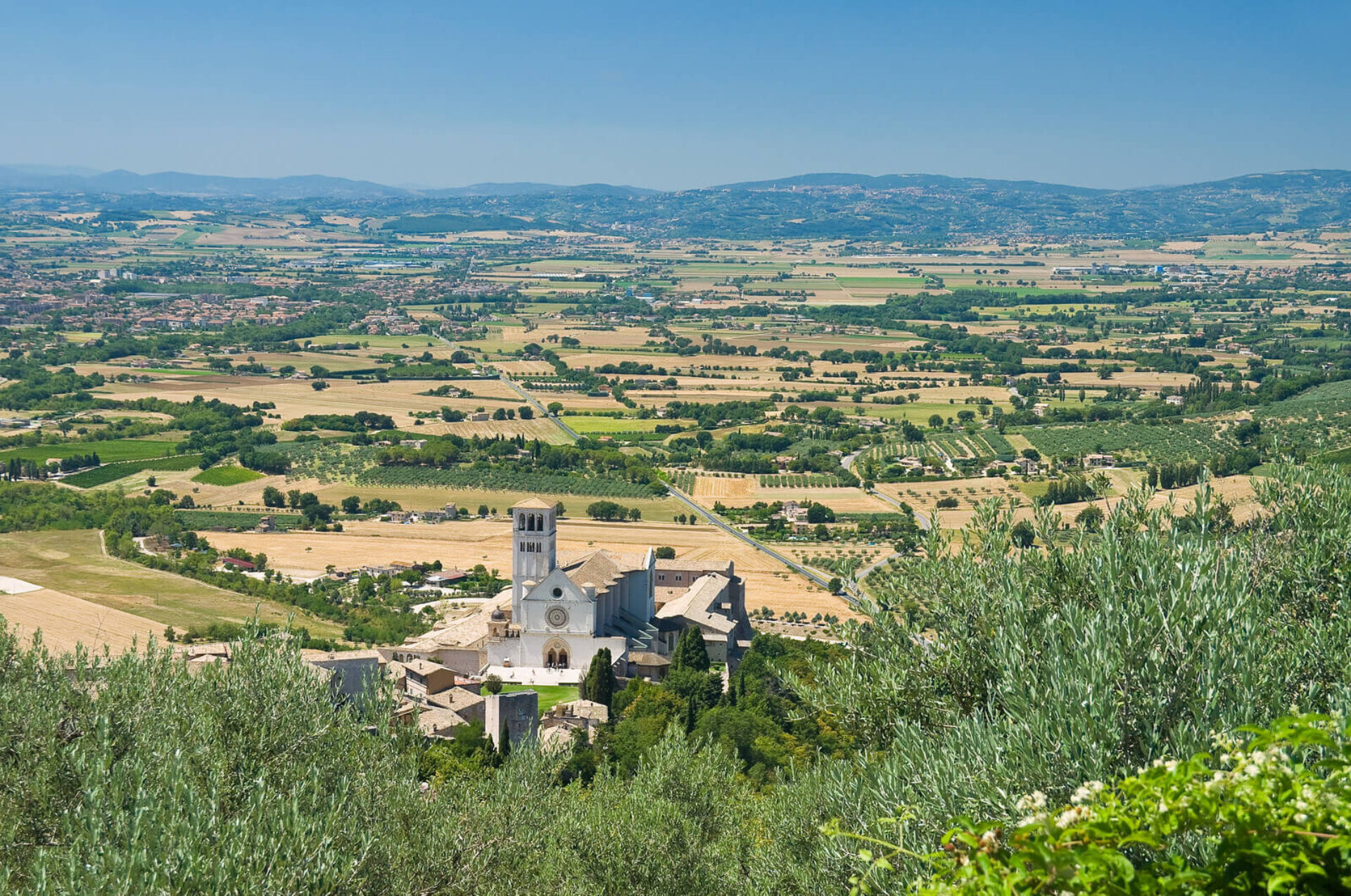 Panorama delle colline umbre con chiesa medievale e valle: il cuore verde dell'Umbria dove vivere esperienze autentiche