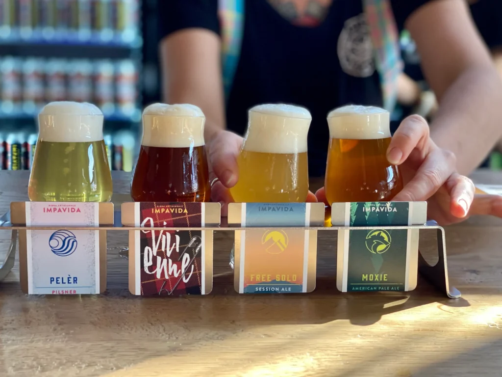 Quattro bicchieri di birra artigianale locale serviti su un vassoio per una degustazione presso un birrificio ad Arco, in Trentino-Alto Adige.