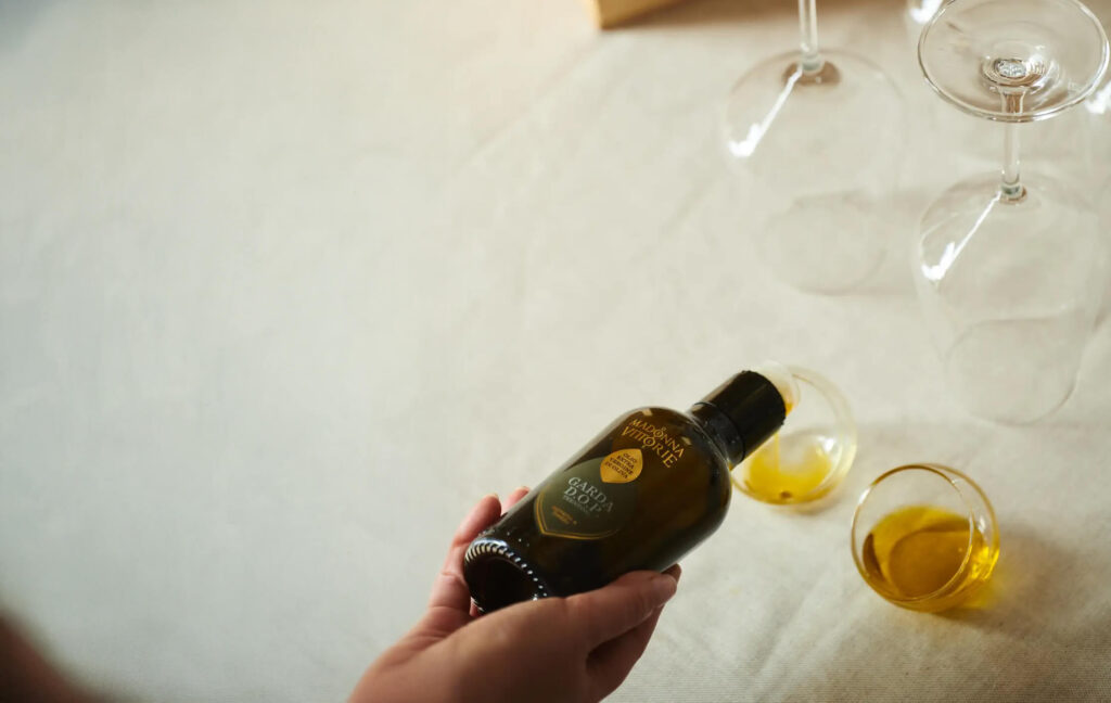Versata di olio extravergine Garda DOP del Trentino in bicchierini da degustazione su tovaglia chiara