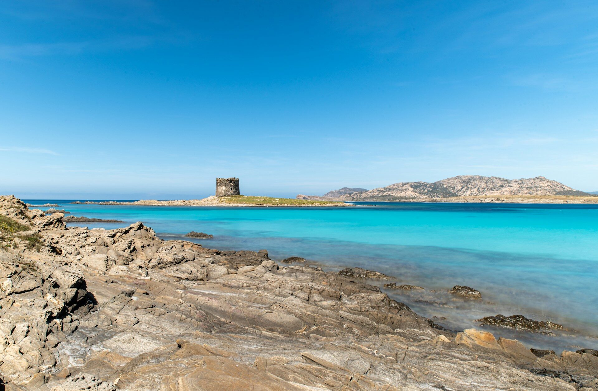 Spiaggia La Pelosa a Stintino con torre aragonese, mare turchese e isola dell'Asinara sullo sfondo, Nord Sardegna