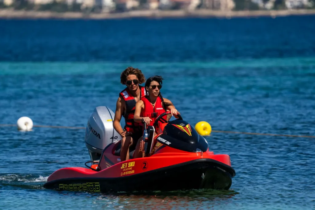 Due ragazzi su una moto d'acqua a noleggio nelle acque cristalline del golfo di Alghero