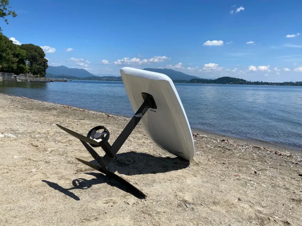 Tavola eFoil con albero e ala anteriore appoggiata sulla spiaggia di un lago