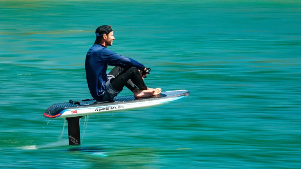 Uomo seduto su un foil board elettrico sulle acque del Lago di Como