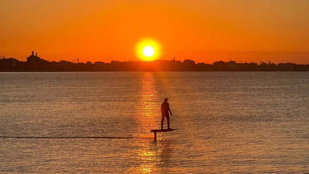 Silhouette di una persona su un eFoil al tramonto sulla costa di Rimini