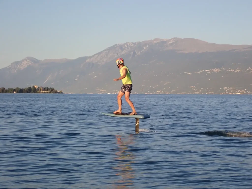 Ragazza che plana su un eFoil sul Lago di Garda con montagne sullo sfondo