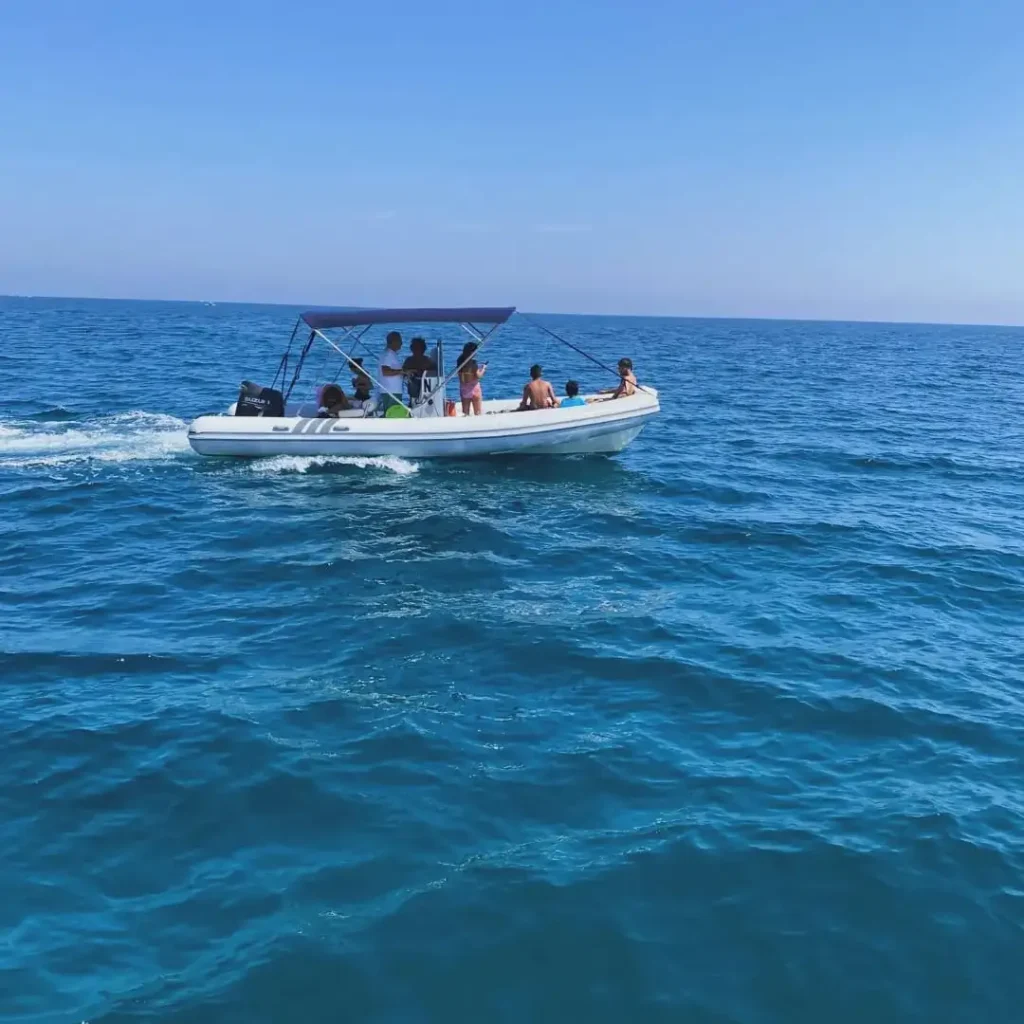 Gommone con turisti in navigazione sul mare cristallino del Salento, escursioni in barca Puglia