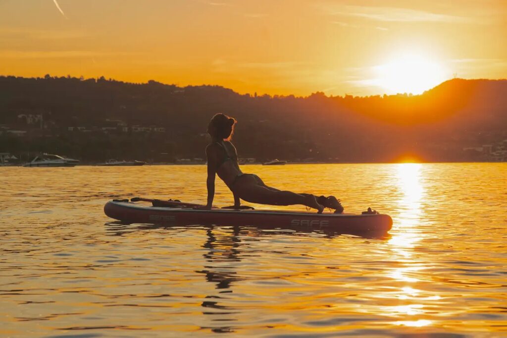 ragazza che fa una posa di yoga su un sup