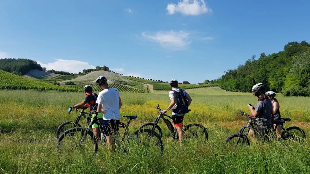 ciclisti in e-bike nel monferrato davanti a paesaggio collinare